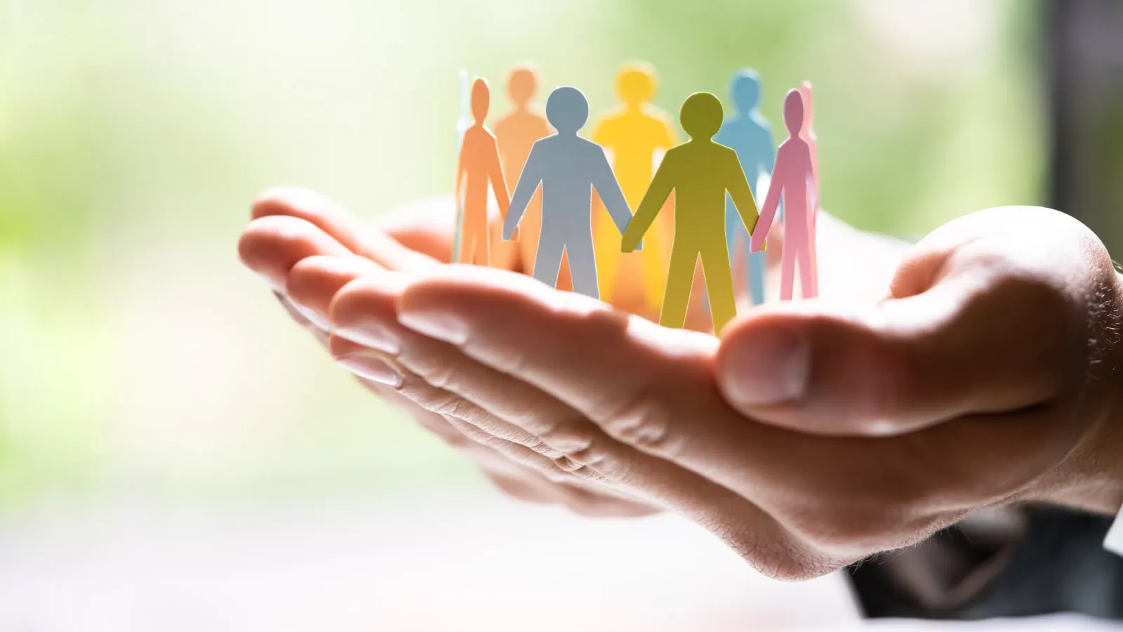 Hand holding paper cut outs of people