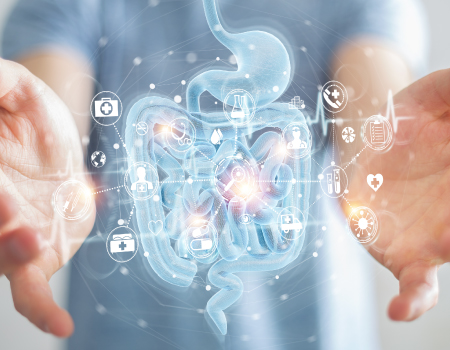 A person holding out their hands with a glowing digital illustration of the digestive system (stomach and intestines) overlaid with healthcare icons and a heartbeat line.